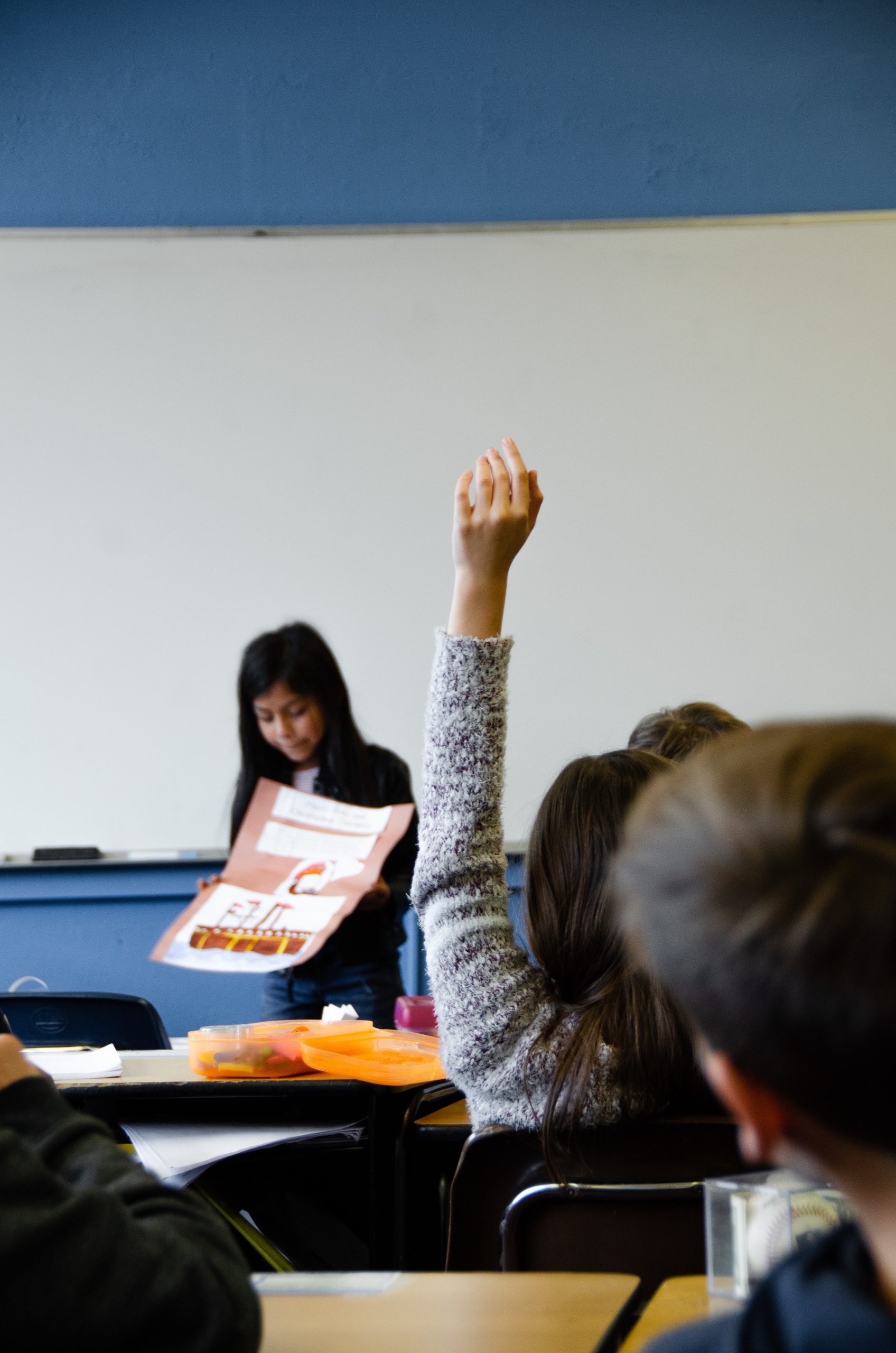 Une élève lève la main pour répondre au professeur.